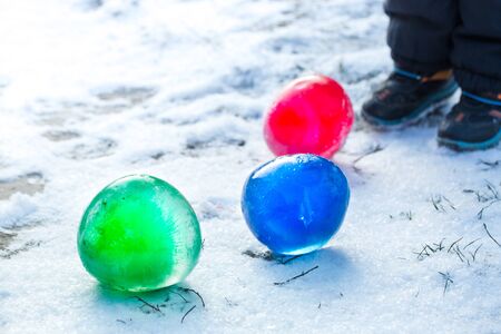 Multi-colored ice balls in the snow on a sunny winter dayの写真素材