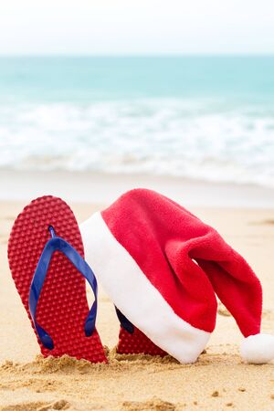 Santa hat and shoes on the sandy ocean. Christmas conceptの写真素材