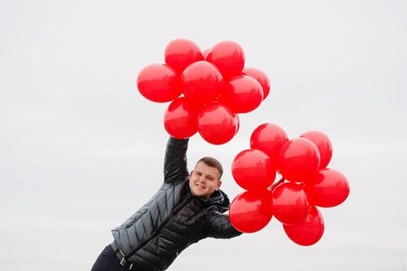 Young man with red balloons in his hands. The concept for St. Valentine's Dayの写真素材