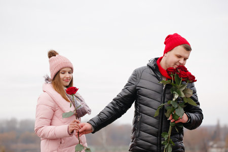 Young beautiful couple with red roses outdoors