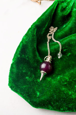 Natural stone pendulum on green velvet, Reiki concept