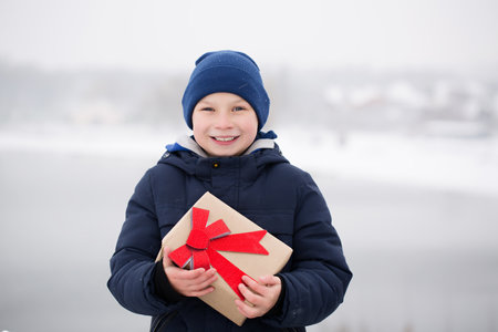 Little boy with a gift in his hands, outdoors in winterの写真素材