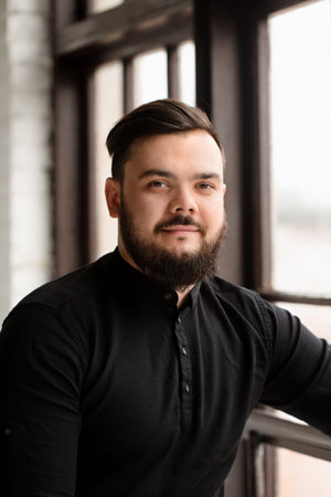 Handsome young guy with a beard in a black shirt. business portrait