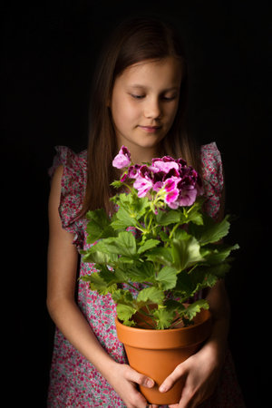 Beautiful little girl with royal pelargonium in her handsの写真素材