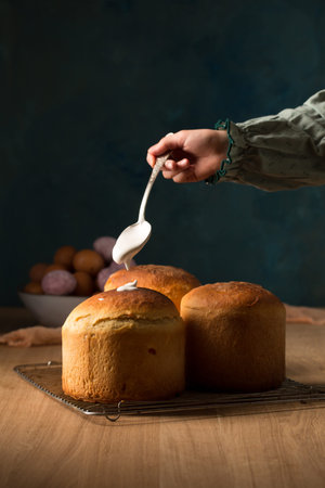 A girl smears Easter cakes with icing, photo in a rustic style