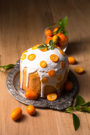 Still life with Easter cake and juicy kumquats on a wooden background