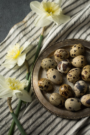 Quail eggs on a metal plate with spring daffodils
