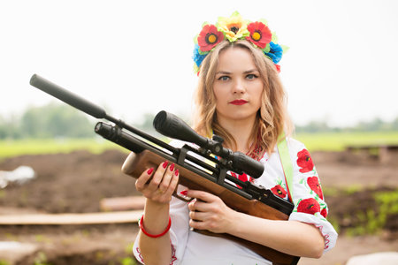 A girl in a Ukrainian national embroidered dress with a weapon in her hands, a symbol of Ukraine...
