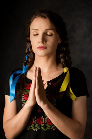 A girl with braided yellow and blue ribbons, the colors of the Ukrainian flag on a dark backgroundの写真素材