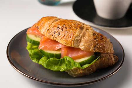 Still life with crispy croissant with salmon and cucumber filling and teaの写真素材