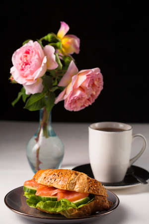 Still life with crispy croissant with salmon and cucumber filling and teaの写真素材