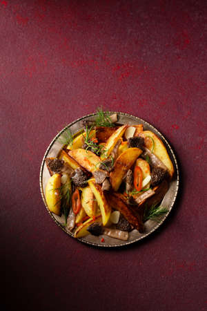 Peasant-style potatoes with wild mushrooms morels seasoned with chili, garlic and greens on a metal plateの写真素材