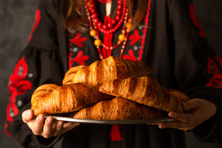 Crispy croissants in the hands of a Ukrainian woman in an embroidered dress