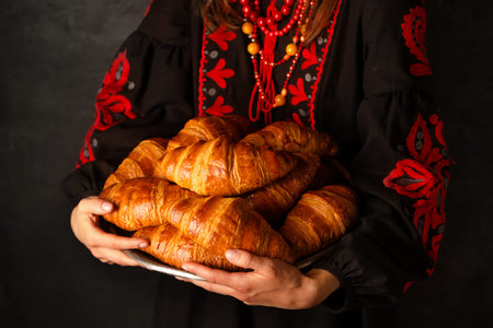 Crispy croissants in the hands of a Ukrainian woman in an embroidered dress