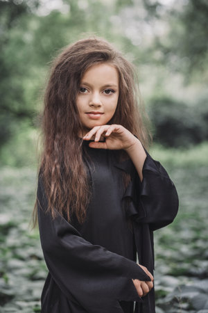Portrait of a charming young witch in the forest. Halloween concept