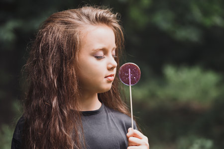 A cute girl in black clothes with a purple candy on a stickの写真素材