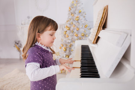 A little girl plays the piano near the Christmas conceptの写真素材