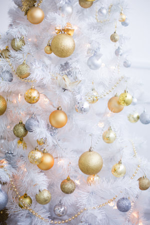 Beautiful white Christmas tree decorated with red and golden balls, close-upの写真素材