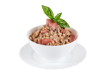 Canned barley porridge with meat and basil in a bowl isolated on white backgroundの写真素材