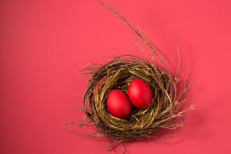 Big red eggs in a small nest on a pink background.