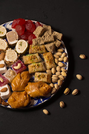 A large plate of various oriental sweets and nuts on a dark backgroundの写真素材
