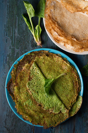 Delicious thin greens pancakes with spinach in a plate on a rustic background