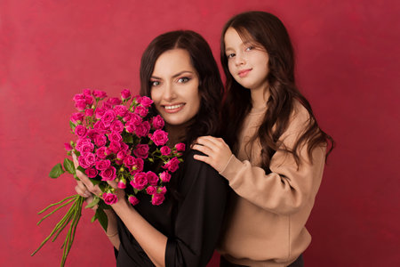 The girl greets her mother with a beautiful bouquet of pink roses on a pink background.の写真素材