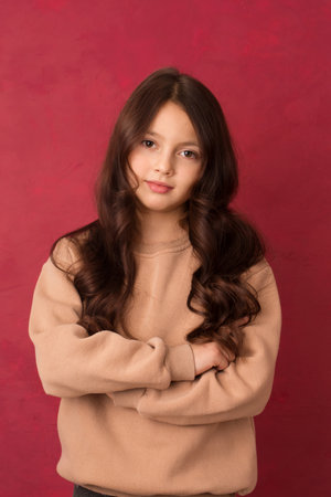 Beautiful positive girl with long curly hair looking at the camera on a pink backgroundの写真素材