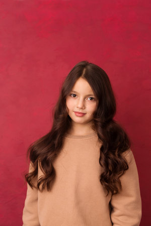 Beautiful positive girl with long curly hair looking at the camera on a pink backgroundの写真素材