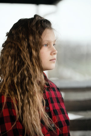 A sad teenage girl with curly messy hair outdoors in windy weatherの写真素材
