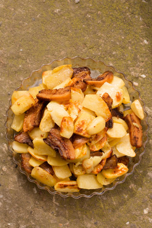 Crispy, ruddy fried potatoes with slices of fried lard on a large plateの写真素材