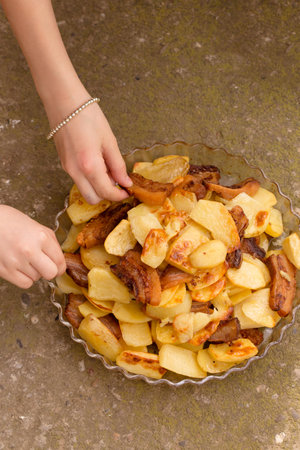 Crispy, ruddy fried potatoes with slices of fried lard on a large plateの写真素材