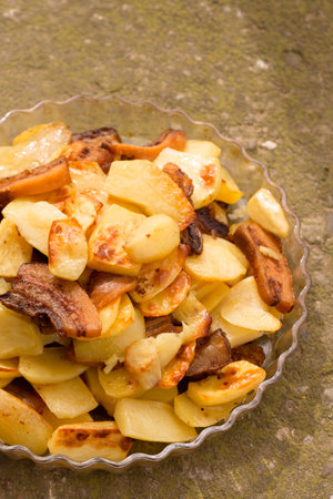 Crispy, ruddy fried potatoes with slices of fried lard on a large plateの写真素材