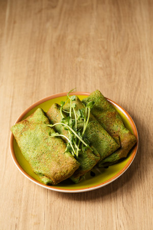 Green pancakes from spinach and young pea shoots in a plate on a wooden tableの写真素材