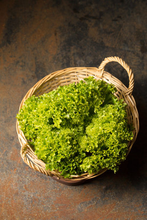 Fresh juicy curly lettuce in basket, photo in rustic style, close-upの写真素材