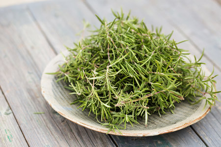 Sprigs of aromatic rosemary in a gray bowl on a wooden backgroundの写真素材