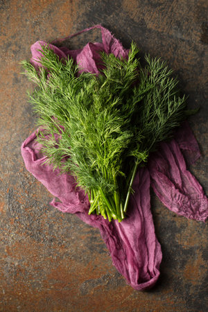A bunch of fresh dill on purple cheesecloth on a metallic backgroundの写真素材