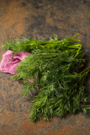 A bunch of fresh dill on purple cheesecloth on a metallic backgroundの写真素材