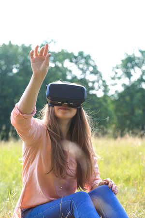 Young beautiful woman wearing virtual reality glasses having fun outdoorsの写真素材