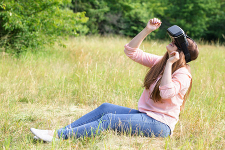 Young beautiful woman wearing virtual reality glasses having fun outdoorsの写真素材