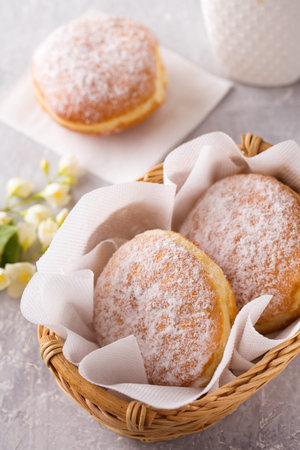 Ruddy delicious donuts berliners with filling sprinkled with powdered sugar in basket on a gray backgroundの写真素材