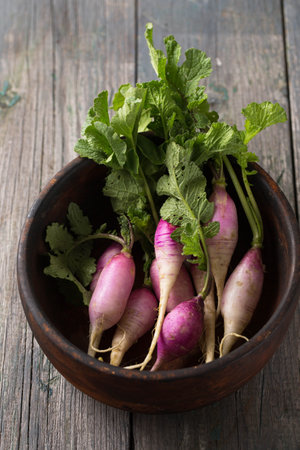 Fresh spring radish with purple-white skin with leaves on a wooden boardの写真素材