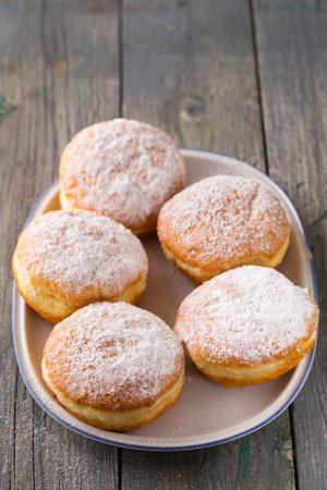 Ruddy delicious donuts berliners with filling sprinkled with powdered sugar on a rustic backgroundの写真素材
