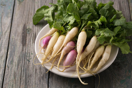 Fresh, white, long radish with leaves on a wooden boardの写真素材
