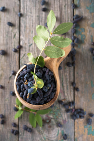Juicy ripe honeysuckle in a wooden cup on a wooden backgroundの写真素材