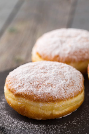 Ruddy delicious donuts berliners with filling sprinkled with powdered sugar on a rustic backgroundの写真素材