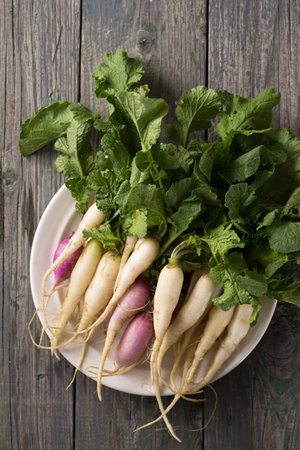 Fresh, white, long radish with leaves on a wooden boardの写真素材