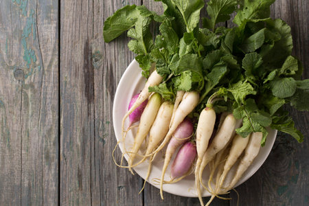 Fresh, white, long radish with leaves on a wooden boardの写真素材