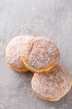 Ruddy delicious donuts berliners with filling sprinkled with powdered sugar on a gray backgroundの写真素材
