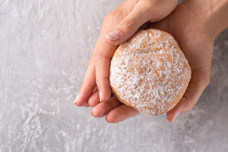 Three donuts in female hands on a gray background, top viewの写真素材